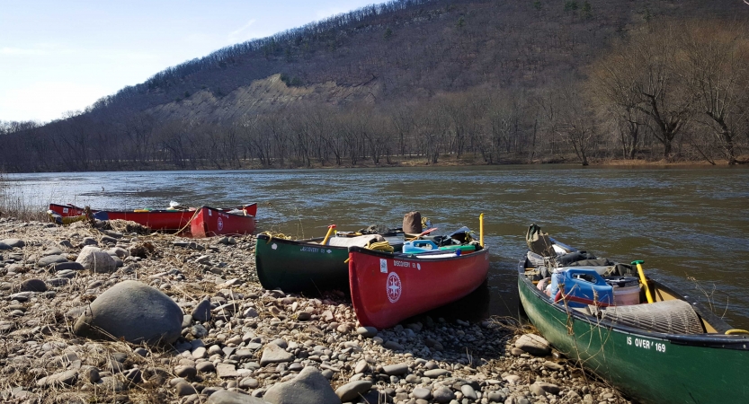 a group of canoes rest on a rocky shore